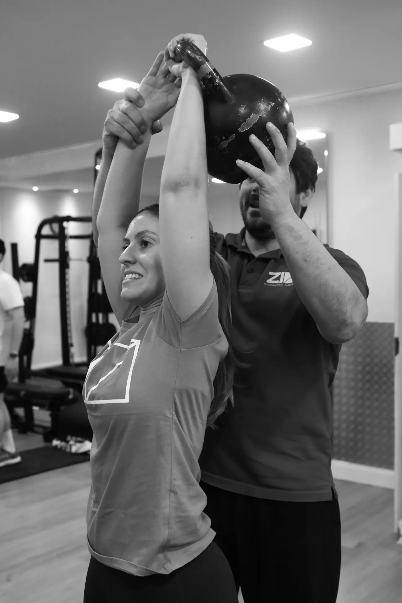 Coach ayudando a una clienta con kettlebell en Z10